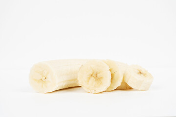 Peeled banana slices are stacked horizontally showing the creamy white flesh isolated on a white background.
