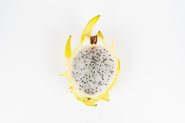 Overhead yellow pitaya half displays white flesh and tiny black seeds isolated on a clean background.