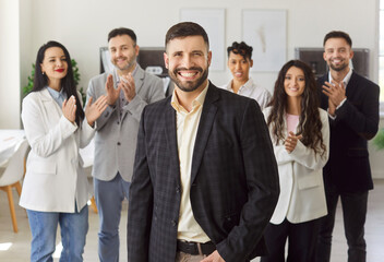 Confident young man standing in front of diverse team members applauding, clap hands,...