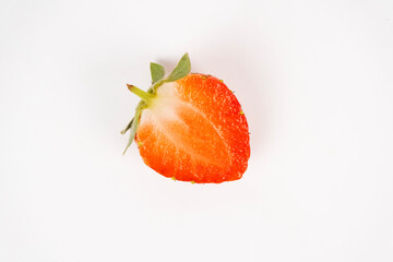 Single strawberry half slice rests on a white background showing bright red flesh and green stem detail.