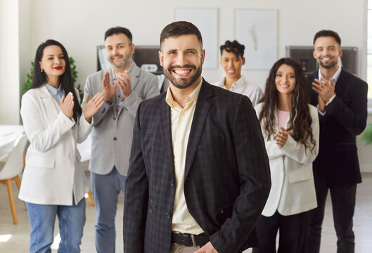 Confident young man standing in front of diverse team members applauding, clap hands, congratulating male colleague with professional success, career growth and promotion. Leadership concept - Powered by Adobe