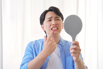 鏡を見る虫歯に悩む男性　20代