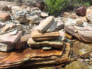 Beautiful rocky seashore with golden-brown stones and clear blue sea. Perfect for nature, geology, and coastal travel photography. Peaceful and scenic seaside landscape background.