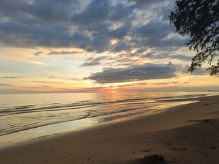 Beautiful sunset over the tropical beach with soft waves and golden sunlight reflections. Perfect for travel, nature, summer, or relaxation themes. Peaceful and inspiring seascape view.