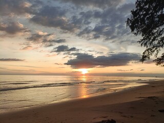 Beautiful sunset over the tropical beach with soft waves and golden sunlight reflections. Perfect for travel, nature, summer, or relaxation themes. Peaceful and inspiring seascape view.