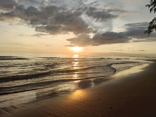 Beautiful sunset over the tropical beach with soft waves and golden sunlight reflections. Perfect for travel, nature, summer, or relaxation themes. Peaceful and inspiring seascape view.