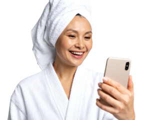 Smiling woman in robe with towel on head video chatting on smartphone against black background