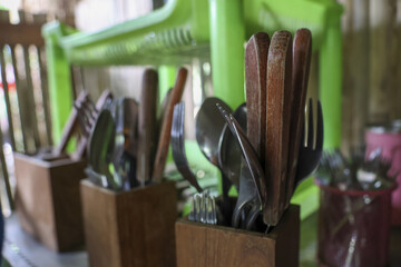 Simple, rustic collection of everyday kitchen cutlery with spoons and forks neatly organized in wooden holder. Homely scene capturing essence of authentic domestic life