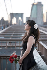 woman holding flowers standing on a beautiful bridge