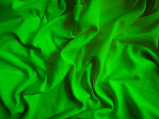 Green crumpled  fabric background. Wavy cloth texture