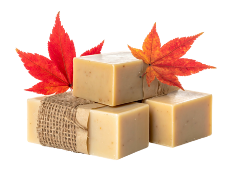 Stack of four rectangular soap bars decorated with orange autumn maple leaves against a black background