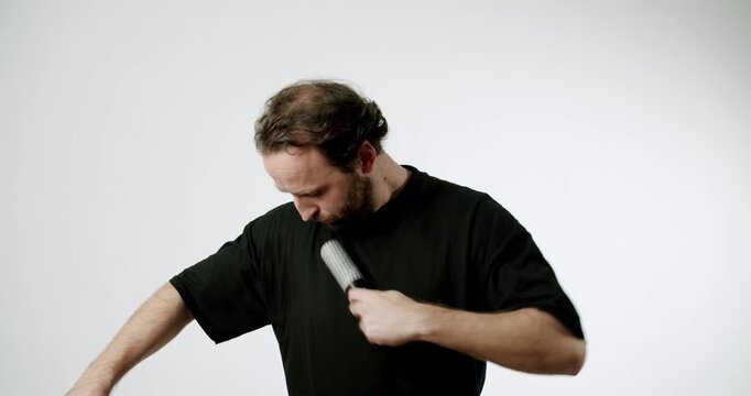 A man uses a lint roller to remove debris from his black t-shirt. He meticulously cleans his sleeve, ensuring a tidy appearance. This simple act is perfect for showcasing cleanliness, self-care,