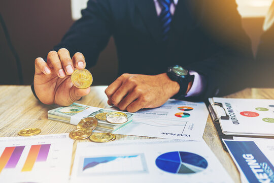 Businessman holding Bitcoin for digital currency trading at his workplace. Bitcoin and digital money concept. - Powered by Adobe
