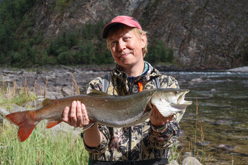 Redefining fishing moments: woman with a rare taimen (Hucho taimen) trophy