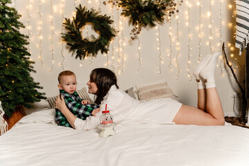 A mother and son are relaxing on their bed on Christmas morning.