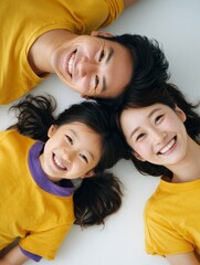 A family of three, a man, a woman and a child, are laying on their stomachs