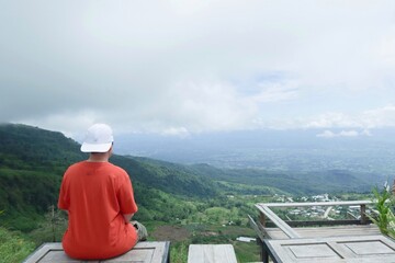 Fototapeta premium Rear view of people sitting and enjoying the mountain view