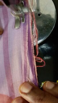 African mending violet fabric with sewing machine in action. Process of sewing, repairing, adjusting, guiding fabric. Macro close up of hands of working dressmaker. Home sewing business tailor at work