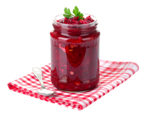 Red beet relish jar on red/white checkered cloth, with parsley garnish and a silver spoon