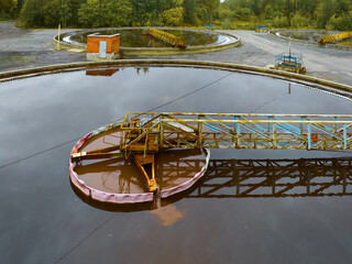 Sewage treatment plant showing large circular tanks and machinery in operation under cloudy skies
