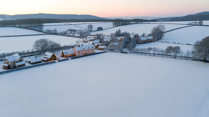 Aerial view of a snow-covered rural village at dusk with fields and houses blanketed in winter
