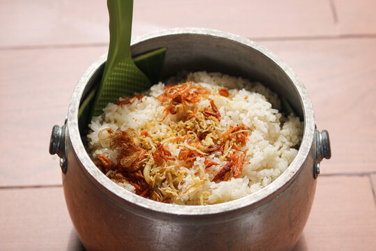 Nasi Liwet, a traditional Indonesian flavored rice dish, served in a rustic metal pot. The rice is generously topped with crispy fried anchovies (ikan teri) and fried shallots (bawang goreng).