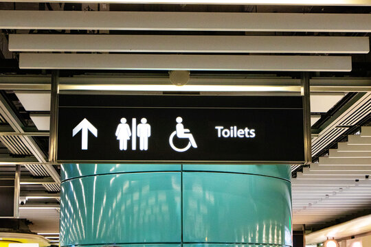 Black signs with white letters symbol icon for modern public toilet or bathroom hanging under ceiling at subway station in Hong Kong. Icon man, woman, people disabilities with person icon. - Powered by Adobe