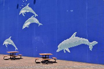 水族館の壁に描かれたイルカの絵の前にあるベンチ