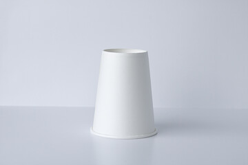 One white, cone-shaped paper cup is arranged upside down on a clean, white background. Suitable for mockups, consumer products, or other concepts. © Ink N Propeller