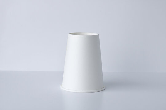 One white, cone-shaped paper cup is arranged upside down on a clean, white background. Suitable for mockups, consumer products, or other concepts.