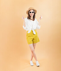 Cheerful beautiful Asian woman showing mini heart sign on beige color background, love concept.