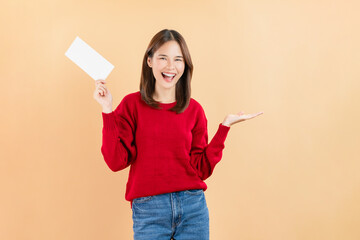 Happy Asian business woman standing and hold blank paper or gift voucher mockup on beige color background.