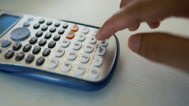 Close-up of a hand pressing buttons on a scientific calculator