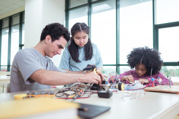 A teacher guiding students in a robotics project during a STEM class in the library