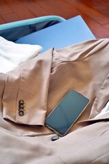 Vertical business essentials—smartphone, suit, and laptop neatly packed in a travel suitcase,...