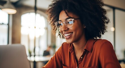 Woman with curly hair wearing glasses and orange shirt