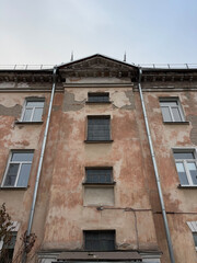 The facade of an old house from which the plaster is falling off