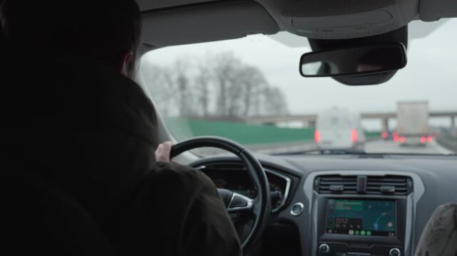 View from inside car showing man driving car on highway with navigation system on display and traffic ahead. Concept of transport, commute and modern driving technology