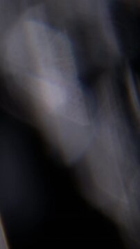 Vertical video. Blur visual dazzle. Art glow. Defocused lens flare flicker blue yellow spectrum texture floating on abstract dark black bokeh light background.