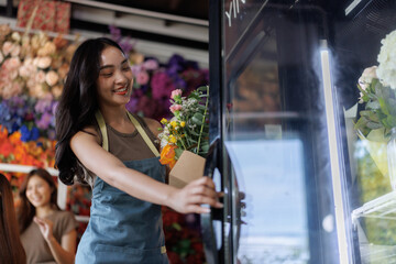 Smiling florist arranging fresh flowers in shop refrigerator
