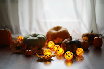 Cozy Autumn Decor with Green and Orange Pumpkins and Glowing Jack-O'-Lantern String Lights on Wooden Floor