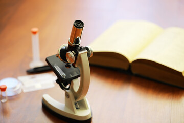 Microscope and Open Book on Wooden Table: Scientific Research Equipment and Study Material