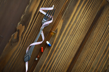 Healthy Eating Concept: Fork with Measuring Tape and Pills on Wooden Table