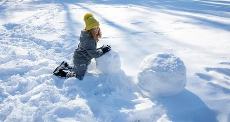 Fotobehang Kasteel Happy winter. Child play with snowball. Kid playing in fresh snow under blue sky. Playful child enjoying sunny winter day in nature. Child building snowman. Child play in snow outdoor.  © Volodymyr