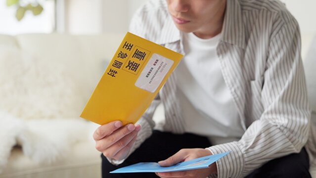 督促状を確認するアジア人男性