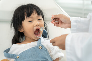 Dentist or dentist treating or examining a little girl teeth, Child receiving treatment from dentist, medicine, dentistry and healthcare, annual checkup, fluoride coating, tooth decayฃ