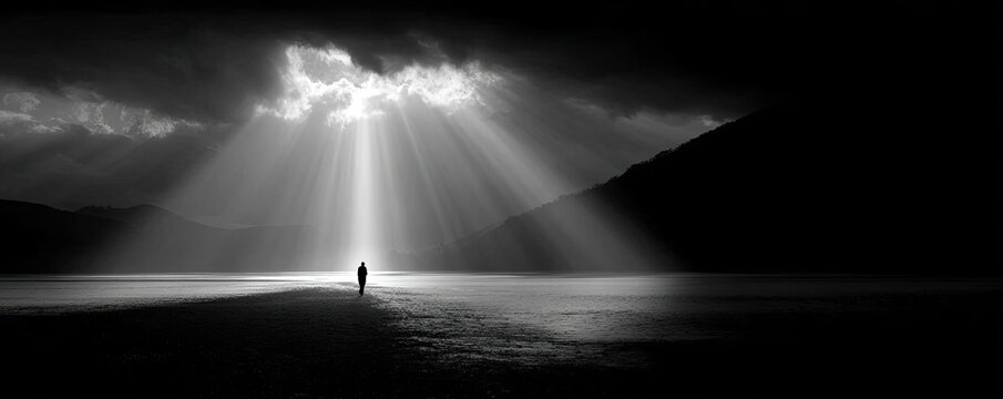 A man walking through a dark valley toward the heavenly concept. A solitary figure stands in a dramatic landscape of light and shadow.