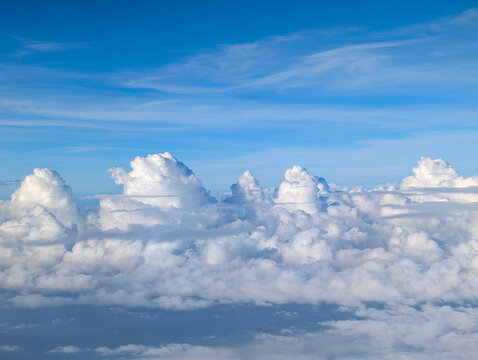 Blue sky above the clouds. View from the plane during the flight of interesting cloud formations, probably cumulus clouds (pile clouds)