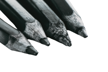 Four charcoal pencils clustered, extreme close-up on tips