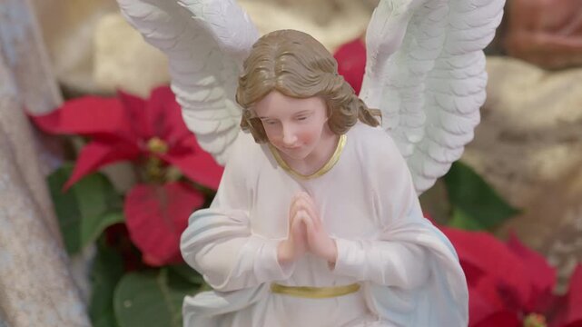 Catholic nativity scene with angels. Christmas religious still life with red flowers prayer and faith detail closeup
